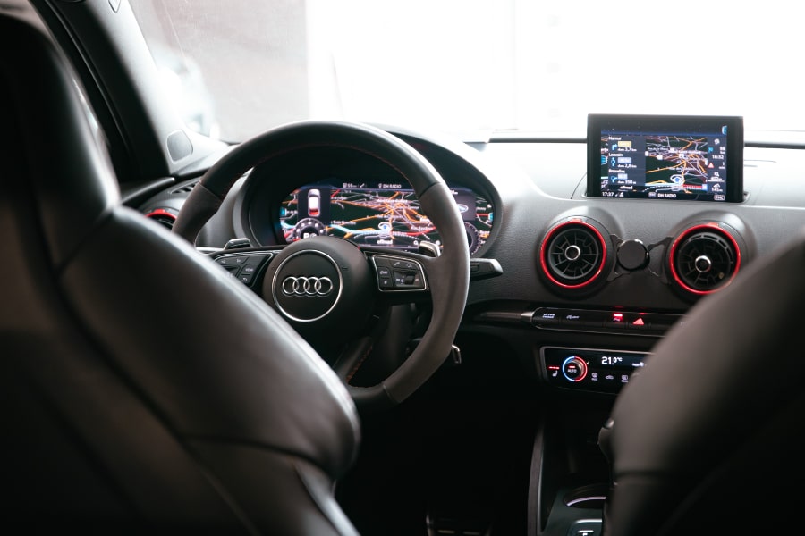 Une voiture sur un élevateur, à côté d'un escalier dans l'entrepot A&D Cars